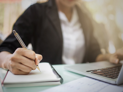 Woman at desk with laptop, notepad and pen