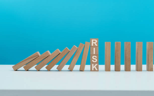 Row of domino blocks one tilting toward a block marked risk